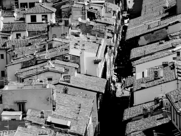 A black and white photograph of a favela in Brazil, taken from a high angle, showing the density of the buildings and the contrast between light and shadow, emphasizing the complex social issues present.