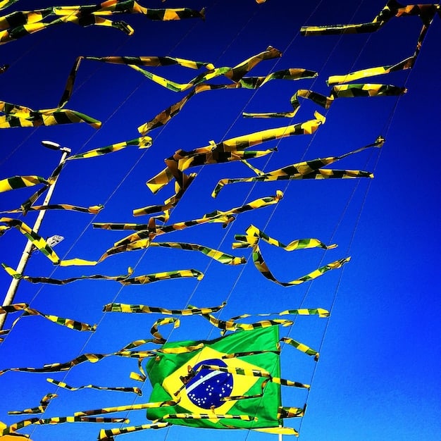 A Brazilian flag subtly integrated into a film reel, symbolizing the national identity within the film industry, with a growth chart superimposed, showing an upward arrow.