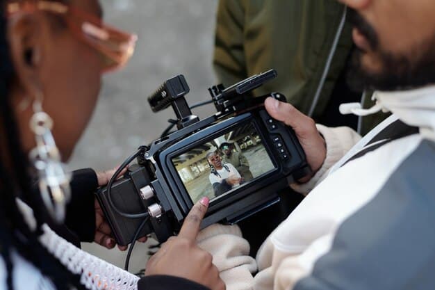 A close-up of a film director's hands using a digital tablet to review production schedules, with a diverse cast and camera crew visible in the blurred background on a film set in Rio de Janeiro.