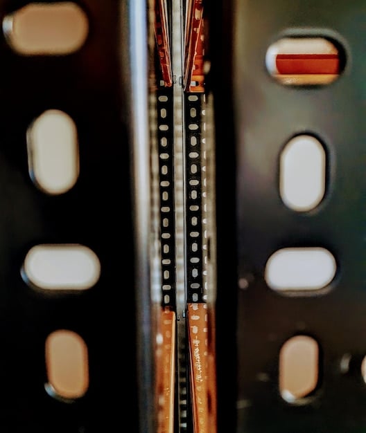 A close-up shot of a film digitization machine in operation, with data cables and computer screens visible in a modern archival setting.