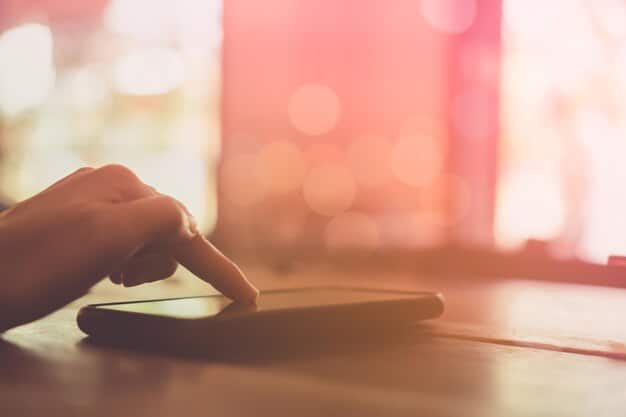 A person's hand swiftly muting a smartphone, with social media icons blurred in the background, signifying a conscious effort to avoid spoilers.