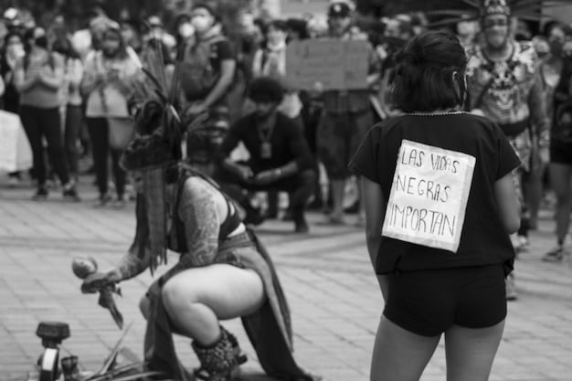 A black and white photo of a protest in Brazil, with people holding signs advocating for freedom of speech and artistic expression. The signs are in Portuguese, and the atmosphere is charged with emotion. The protest is directly related to the Censorship Controversy: Government Reviewing Content of Upcoming Brazilian Documentary.