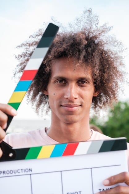 A close-up of a young Brazilian filmmaker accepting an award at a film festival. The filmmaker is holding the award with a proud and happy expression. The background shows the stage and audience, creating a sense of achievement and recognition. The image relates to the section by showing the success of new talent at Brazilian film festivals.