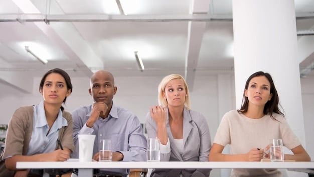 A group of Lumon Industries employees sitting in a sterile, white conference room, their faces reflecting a mix of confusion and resignation, illustrating the show's exploration of corporate control and the erosion of personal identity in 'Severance' Season 2: What to Expect from the Mind-Bending Thriller.